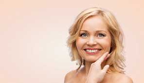 beauty, people and skincare concept - smiling woman with bare shoulders touching face over beige background