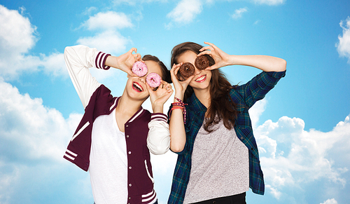 people, friends, teens and friendship concept - happy smiling pretty teenage girls with donuts making faces and having fun over blue sky and clouds background