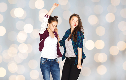 people, fun, teens and friendship concept - happy smiling pretty teenage girls dancing over holidays lights background