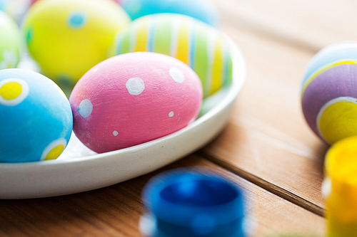 easter, holidays, tradition and object concept - close up of colored easter eggs on plate