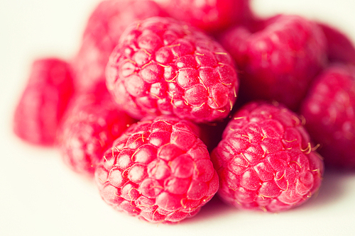 fruits, berries, ,  food and objects concept - juicy fresh ripe red raspberries on white