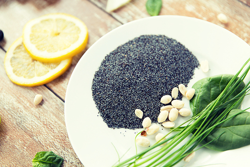 healthy eating, vegetarian super food, culinary and diet concept - close up of peeled peanuts, greens and poppy or chia seeds