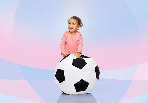 childhood, game, sport, football and people concept - happy african american little baby girl playing with ball over pink violet background