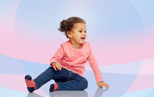 childhood, fashion, clothing and people concept - smiling beautiful african american little baby girl sitting on floor over pink violet background