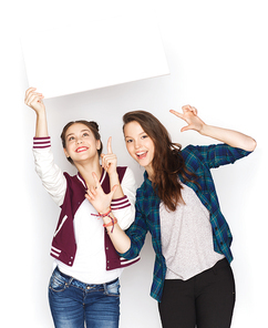 people, friends, teens and friendship concept - happy smiling pretty teenage girls holding and showing white blank board