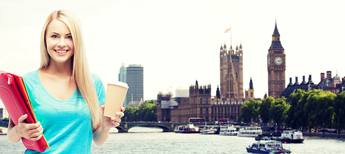 education, school, study abroad, drinks and people concept - smiling student girl with folders and cup of coffee over london city background
