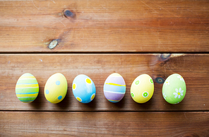 easter, holidays, tradition and object concept - close up of colored easter eggs on wooden surface with copy space