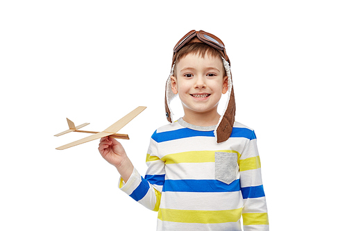 childhood, fashion and people concept - happy smiling little boy in aviator hat playing with wooden airplane