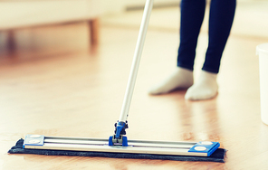 people, housework and housekeeping concept - close up of woman legs with mop cleaning floor at home