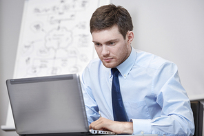 business, people and work concept - businessman sitting with laptop computer in office in front of whiteboard