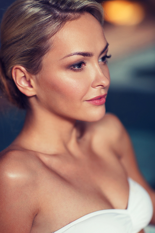 people, beauty, spa, healthy lifestyle and relaxation concept - close up of beautiful young woman in swimsuit at swimming pool