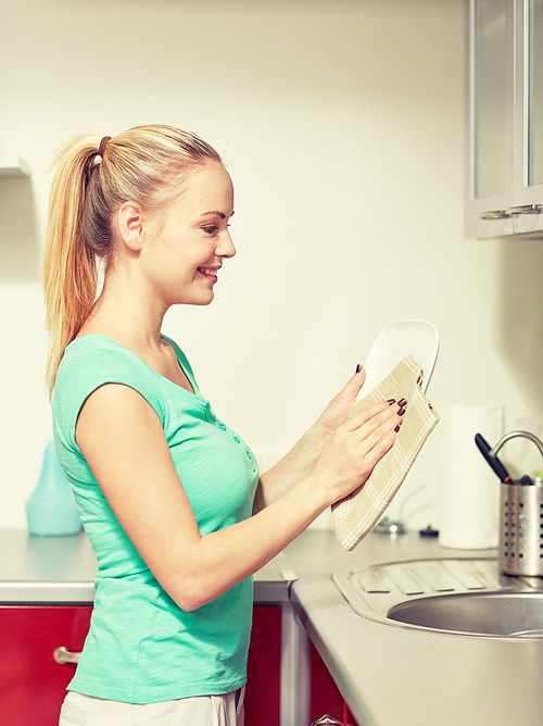 people, housework and housekeeping concept - happy woman wiping dishes at home kitchen