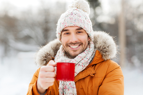 people, season, drinks and leisure concept - happy man with tea cup  in winter