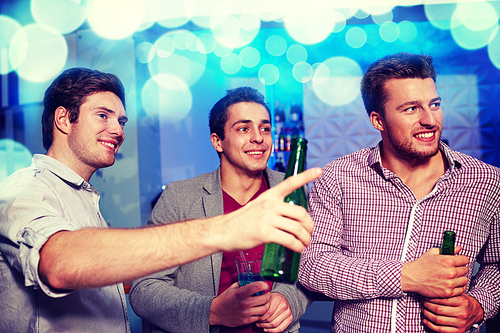 nightlife, party, friendship, leisure and people concept - group of smiling male friends with beer bottles drinking in nightclub