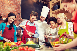 cooking class, culinary, food and people concept - happy group of friends and male chef cook cooking in kitchen