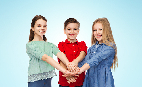 childhood, friendship and people concept - happy smiling boy and girls with hands on top over blue background