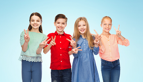 childhood, friendship and people concept - happy smiling boy and girls showing peace hand sign over blue background