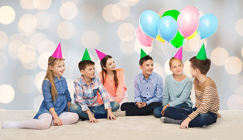 childhood, holidays, friendship and people concept - happy smiling children in party hats on birthday over lights background