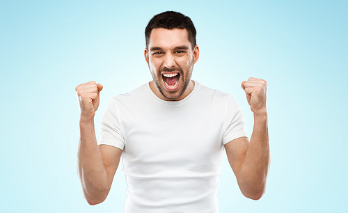 emotion, success, gesture and people concept - young man celebrating victory over blue background