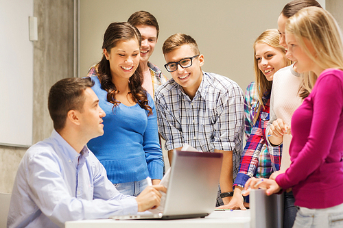 education, high school, technology and people concept - group of smiling students and teacher with papers, laptop computer in classroom