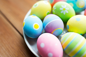 easter, holidays, tradition and object concept - close up of colored easter eggs on plate