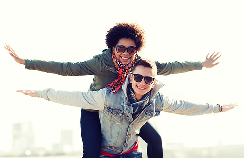 friendship, leisure, international, freedom and people concept - happy teenage couple in shades having fun outdoors