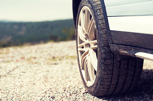 transport, driving and motor vehicle concept - close up of dirty car wheel on cliff