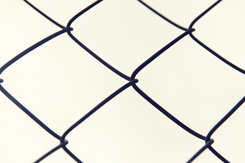 captivity, prison and obstruction concept - close up of mesh fence over gray sky