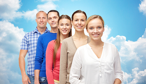 family, gender and people concept - group of smiling men and women over blue sky and clouds background