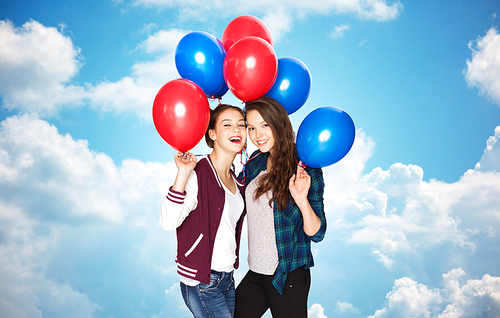 people, friends, teens, holidays and party concept - happy smiling pretty teenage girls with helium balloons over blue sky and clouds background