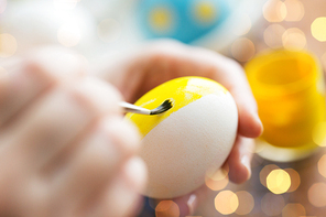 easter, holidays, tradition and people concept - close up of woman hands coloring easter eggs with colors and brush