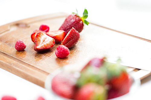 fruits, berries, weight loss,  food and objects concept - close up of fresh ripe red strawberries on cutting board