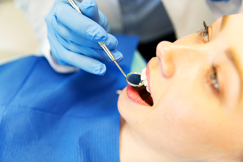 people, medicine, stomatology and dentistry concept - close up of dentist hand with mouth mirror checking female patient teeth up at dental clinic office