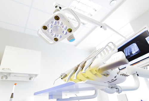 dentistry, medicine, medical equipment and stomatology concept - close up of lamp and dental unit instruments clinic office