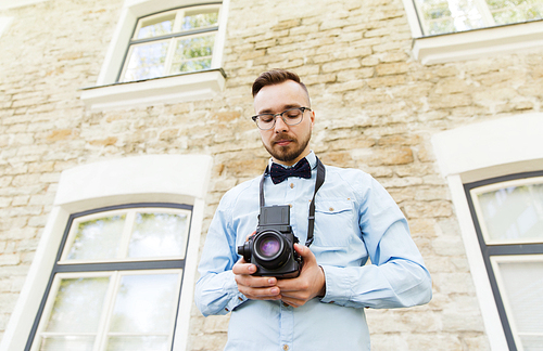 people, photography, technology, leisure and lifestyle - happy young hipster man with retro vintage film camera on city street