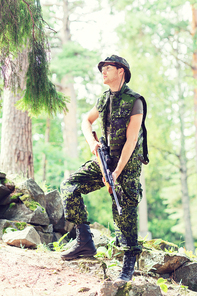 hunting, war, army and people concept - young soldier, ranger or hunter with gun in forest