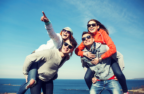 friendship, leisure and people concept - group of happy teenage friends in sunglasses having fun outdoors