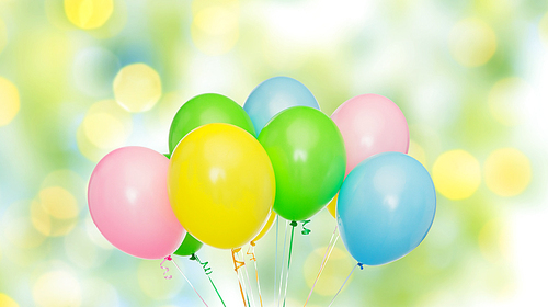 holidays, birthday, party and decoration concept - bunch of inflated colorful helium balloons over green summer lights background