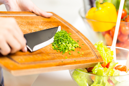 healthy eating, cooking, vegetarian food, diet and people concept - close up of woman adding chopped green onion to salad