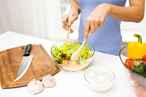 healthy eating, vegetarian food, dieting and people concept - close up of young woman cooking vegetable salad at home