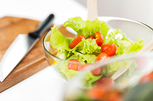 diet, vegetable food, healthy eating and objects concept - close up of vegetable salad with cherry tomato and lettuce in glass bowl