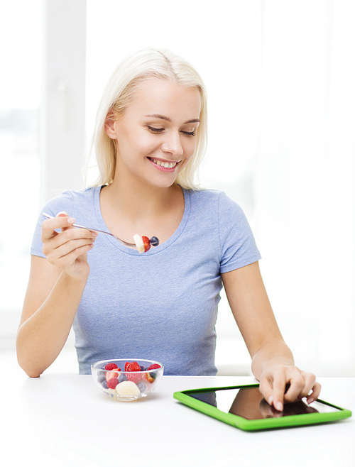 healthy eating, dieting and people concept - smiling young woman with tablet pc computer eating fruit salad at home