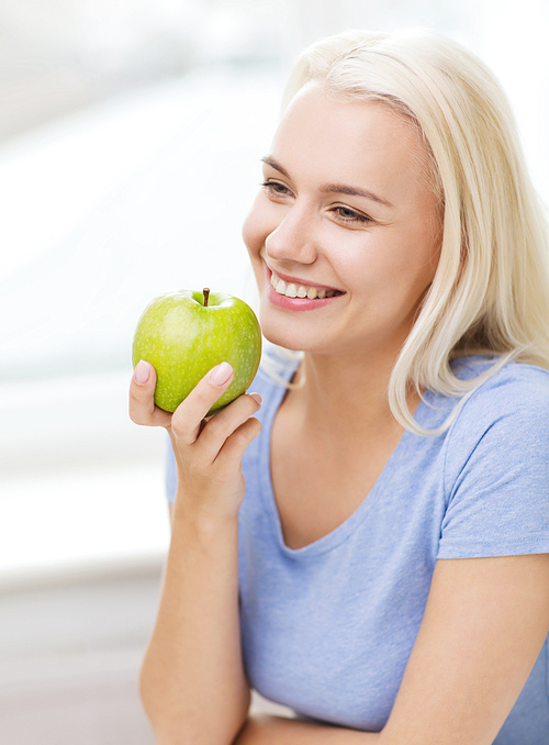 healthy eating, organic food, fruits, diet and people concept - happy woman eating green apple at home