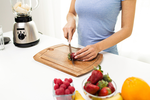 healthy eating, cooking, vegetarian food, weight lossing and people concept - close up of woman chopping strawberry at home