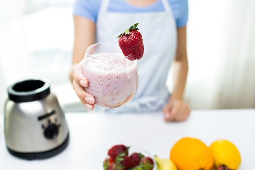 healthy eating, cooking, vegetarian food, weight lossing and people concept - close up of woman holding glass of fruit strawberry shake at home