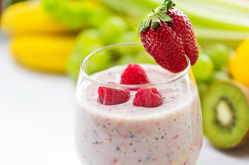 healthy eating, cooking, vegetarian food, ing and people concept - close up of glass with strawberry milk shake and fruits