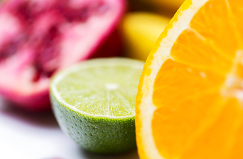 healthy eating, food, fruits and diet concept - close up of fresh juicy orange and lime