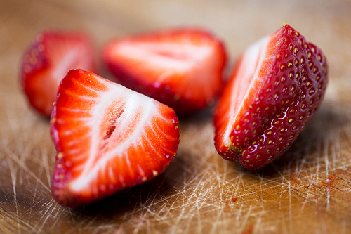 fruits, berries, diet,  food and objects concept - close up of fresh ripe red strawberries on cutting board