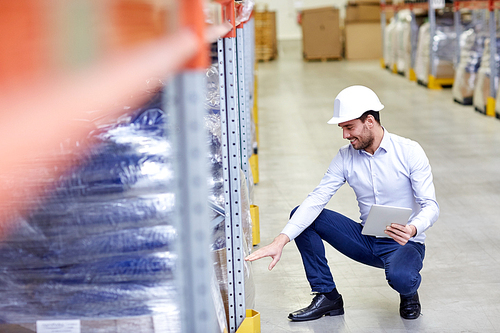 wholesale, logistic, business, export and people concept - happy man or manager with tablet pc computer checking goods at warehouse