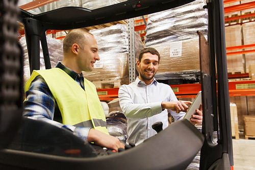 wholesale, logistic, loading, shipment and people concept - smiling loader on forklift and businessman with tablet pc computer at warehouse